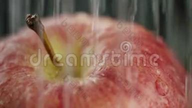 在<strong>视频</strong>中，我们看到一个红苹果，水<strong>开始</strong>从顶部倾泻，就像一个坚硬的淋浴，黑色的背景，特写。
