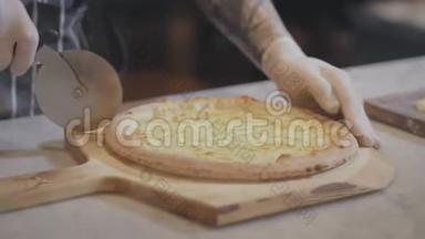 厨师手在手套切割热比萨饼基地通过滚动比萨饼切割机，特写。 熟练的皮萨约罗在