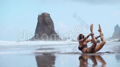 一位身穿泳装的美女在海滩上表演一座运动桥，桥上环绕着黑色的火山沙