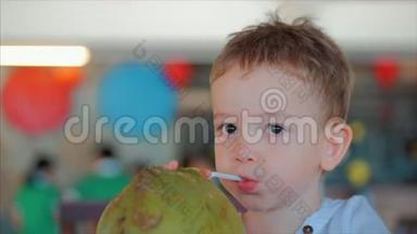 可爱的孩子喝椰子槽一根稻草，特写。 概念：孩子，快乐童年，夏天，宝宝，假期..