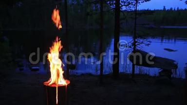瑞典或芬兰圆木蜡烛靠近黄昏湖。 夜晚从木头里燃烧起来。