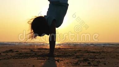 小女孩在海滩上做倒立姿势的剪影，特写