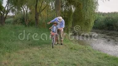 父亲和儿子一起学习骑自行车，在户外自然和小河边玩得开心