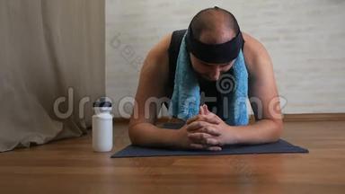 有趣的胖子在瑜伽垫上厌倦了上课，用水，冷却自己
