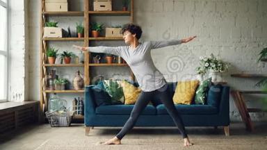漂亮的女孩正在家里做瑜伽练习，伸展身体，站在家里的地板上集中练习。 青年