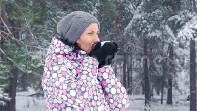 一个年轻的女<strong>游客</strong>在冬天的<strong>森林</strong>里喝热茶在降雪。