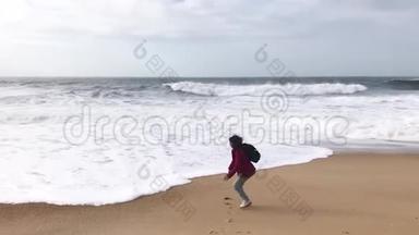 一个年轻的女人，背着背包在<strong>海边玩</strong>海浪。
