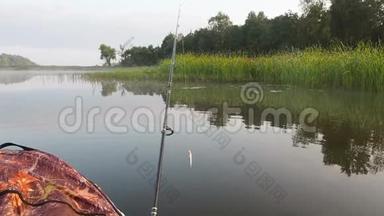 一个人在河上的充气船上钓鱼。 夏天人们坐着充气皮艇在河边休息