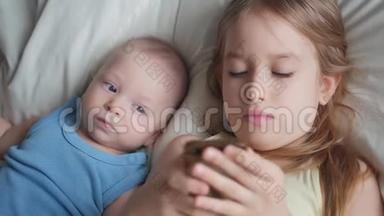 两个孩子在<strong>床上</strong>一起使用和<strong>玩手机</strong>。 孩子们在卧室的<strong>床上</strong>一起用电话