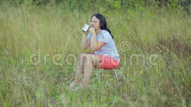 年轻女子坐在<strong>林间</strong>空地上喝茶享受。