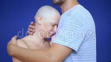 <strong>男人</strong>在蓝色背景上拥抱一个悲伤的<strong>秃头</strong>女人。 肿瘤学的概念和化疗的效果。