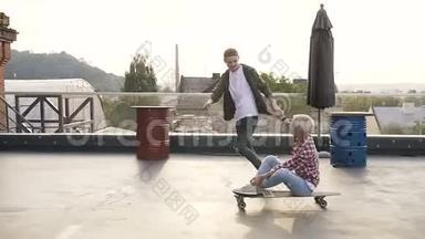 英俊的年轻人和他的女孩在工业大厦屋顶的滑板上玩得很<strong>开心</strong>。 两个人玩得<strong>开心</strong>