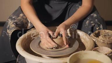 这个女孩在陶工`的轮子上做了一壶粘土。 双手特写