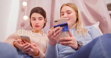 两个女孩，女朋友躺在粉红色卧室的床上，手里拿着电话，滚动着