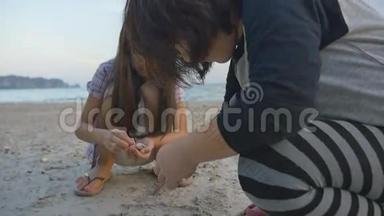 亚洲小孩在沙滩上捡贝壳