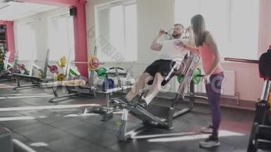 他和私人教练在<strong>健身</strong>房的训练模拟器上摆动腿部肌肉。 个人<strong>减肥</strong>训练