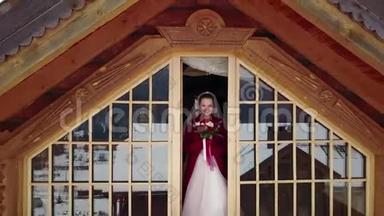 无人机的镜头从美丽的新娘身上飞过，她站在木屋的阁楼上，<strong>露出</strong>了那座山