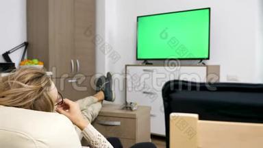 幸福的一对夫妇在他们舒适的公寓里看着绿色<strong>屏</strong>幕的<strong>大屏</strong>幕<strong>电视</strong>