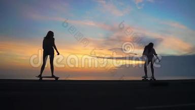 <strong>日</strong>落时分，两个女孩坐在<strong>滑板</strong>上，靠着岩石和天空在路上行走
