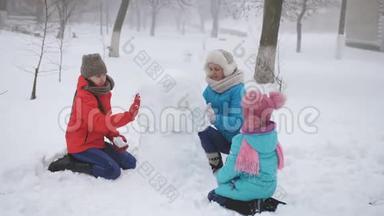 妈妈和两个女儿在冬天堆雪人。