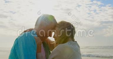 活跃的高加索族夫妇在海滩上互相拥抱的侧面景色