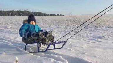 坐雪橇的小男孩。 宝贝在雪橇上。 孩子们在雪地里户外玩耍。 愉快的寒假。 冬季