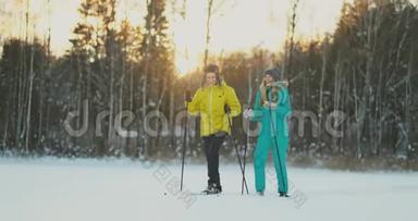 年轻夫妇载着滑雪板在美丽的冬林中聊天，复制空间的侧视图