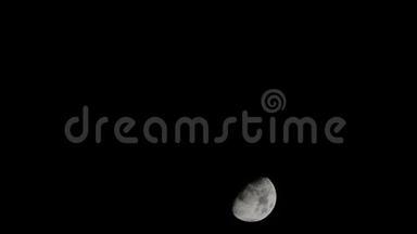 夜晚黑暗天空中的半个月亮快速地向下移动，乌云在风中移动