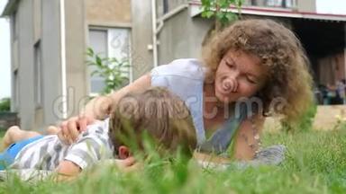 简单的育儿观念。 快乐的母子躺在草地上..