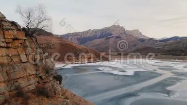 以史诗般的岩石和悬崖为背景，在冻结的山湖畔鸟瞰山坡和悬崖。