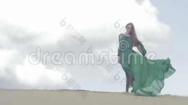 女孩站在沙丘上穿着绿色的衣服，风