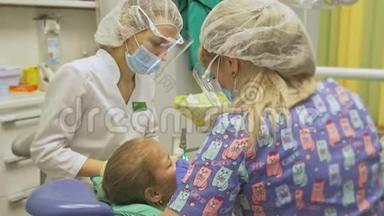带着一个母亲的孩子在牙医`<strong>接待处</strong>。 女孩躺在椅子上，在她母亲的身后。 医生和一个