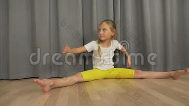 <strong>小女孩</strong>在室内起居室里做劈腿和伸展运动。快乐的<strong>小女孩</strong>坐着<strong>跳舞</strong>。