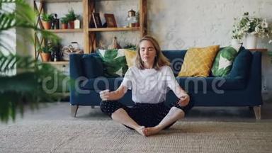 漂亮的年轻女子在家练习瑜伽，以简单的身体姿势放松，坐在地板上，带着漂亮的家具