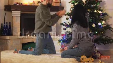 有趣的情侣在家装饰圣诞树。 快乐的一对夫妇准备圣诞晚会。 居家休闲理念
