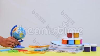 桌子上有写字的材料一个孩子`手把地球仪放在桌子上