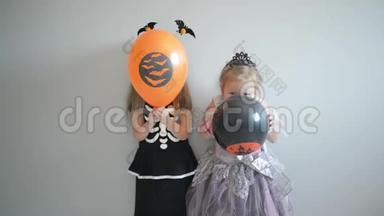 <strong>两个</strong>微笑的小女孩穿着万圣节服装，拿着气球和<strong>拳头</strong>。