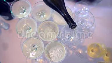 带酒杯的桌子和香槟酒，用于婚礼。 服务员把香槟倒进玻璃杯里。 香槟酒滑梯