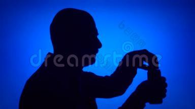 老人打开蓝色背景啤酒罐的剪影。喝苏打水的男人脸
