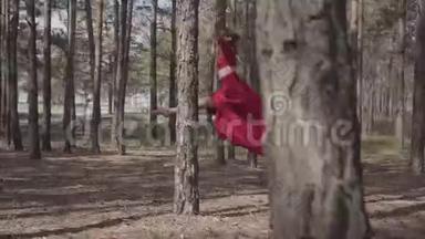优雅的女人穿着红色的衣服在森林里跳舞。 很漂亮的<strong>当代舞者</strong>。 优雅的女孩奔跑跳跃