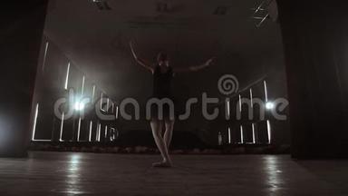 慢动作：穿黑色连衣裙的首席芭蕾舞演员表演旋转和优雅的舞蹈动作。 相机<strong>继续前进</strong>
