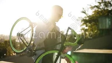 一个穿着便装、戴着墨镜、英俊的<strong>白种人</strong>年轻男子正在上楼的<strong>时候</strong>，他正肩搭着一辆自行车