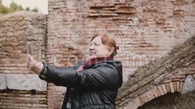 令人兴奋的高级高加索旅游妇<strong>女自拍</strong>使用智能手机在历史悠久的古代遗址奥斯蒂亚，意大利。