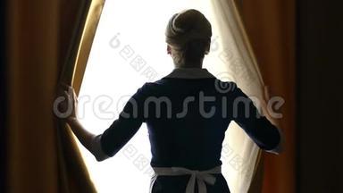 豪华酒店的女服务员打开最合适的窗帘，准备打扫房间