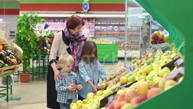 快乐的老妇人带着孙子在超市买水果。