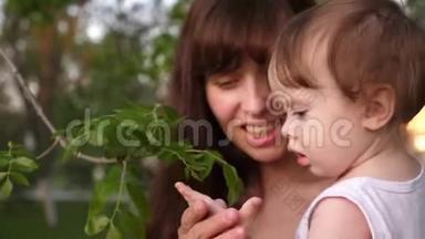 妈妈在树枝上给小孩子看<strong>一片绿叶</strong>。 小女孩在和她妈妈玩。