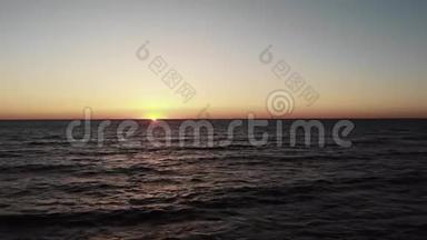 红色的太阳落在海面上，海面上有波浪，地平线上有一艘黑色的小游艇。 日落与太阳之路，太阳之路海滨。