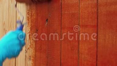 画家用棕色或红色的醇酸漆画一堵墙或木条栅栏。