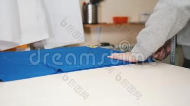服装厂的工人整齐地把一块蓝色的布放在桌子上