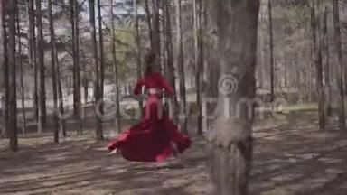 技巧优雅的女人穿着红色的裙子在森林景观中跳舞。 很漂亮的当代舞者。 优雅的女孩跑来跑去